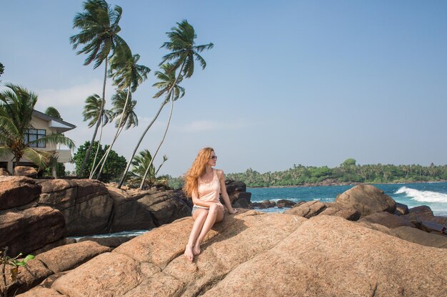 Portrait de jeune femme en bikini blanc sur la plage tropicale en regardant la caméra Belle fille latine en maillot de bain avec espace de copie Vacances d'été et concept de bronzage