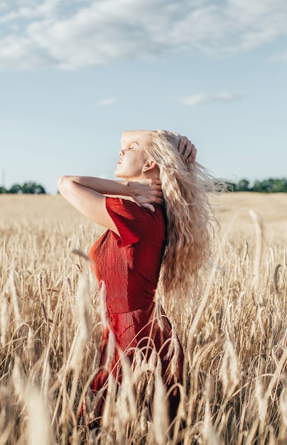 Portrait de jeune femme blonde dans un champ de blé en été