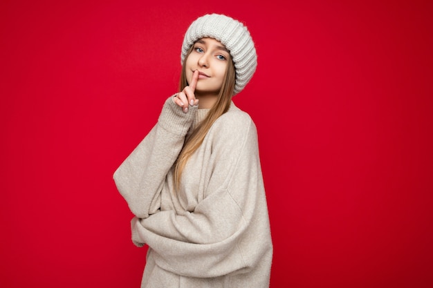 Portrait de jeune femme blonde foncée séduisante positive avec des émotions sincères portant un pull beige