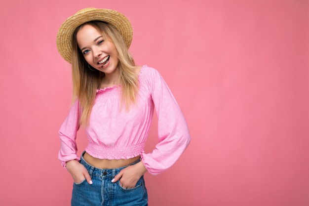 Portrait de jeune femme blonde hipster souriante séduisante en haut court rose élégant et chapeau de paille