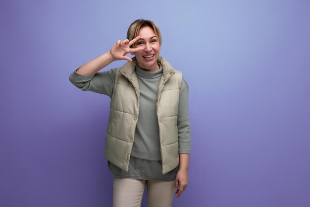 Portrait d'une jeune femme blonde joyeuse dans un gilet beige sur fond bleu