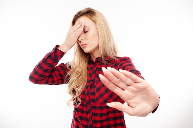 Portrait de jeune femme blonde montrant un panneau d'arrêt avec la main isolé sur fond blanc