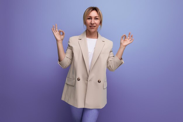 Portrait d'une jeune femme blonde positive européenne soignée dans une pose zen sur fond de studio