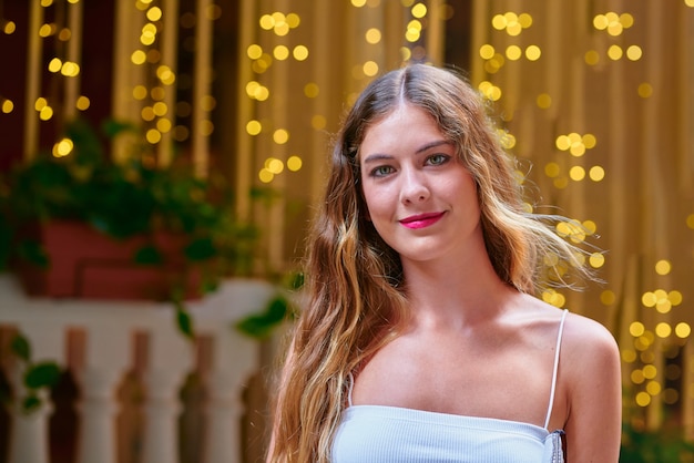 Portrait de jeune femme blonde regardant la caméra et souriant vêtu d'un haut blanc