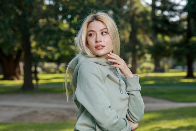 Portrait de jeune femme blonde se tenir au parc