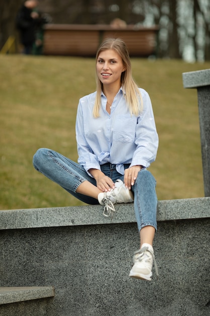 Portrait d'une jeune femme blonde souriante sur fond urbain.