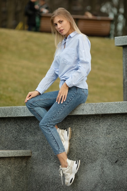 Portrait d'une jeune femme blonde souriante sur fond urbain.