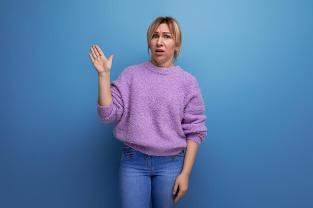 Portrait d'une jeune femme blonde triste effrayée dans un chandail de lavande sur un fond uni lumineux