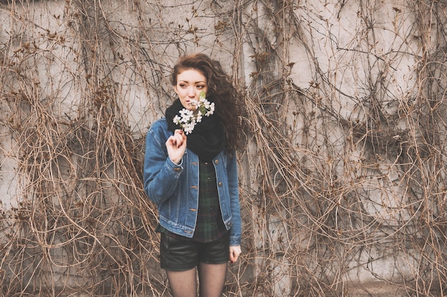 Portrait d'une jeune femme avec une branche lilas debout dans un parc de la ville