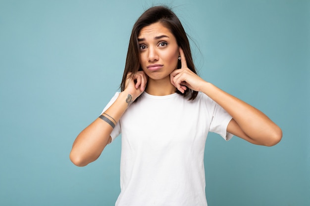 Portrait de jeune femme brune assez agréable avec des émotions sincères portant un t-shirt blanc décontracté