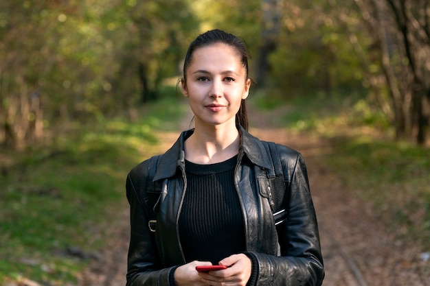 Portrait de jeune femme brune en blouson de cuir. Une jeune femme élégante se promène dans le parc en automne.