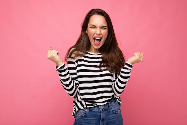 Portrait de jeune femme brune heureuse et positive avec des émotions sincères portant un pull rayé décontracté