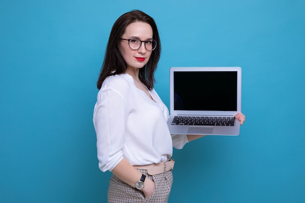 Portrait d'une jeune femme brune avec un ordinateur portable sur fond bleu