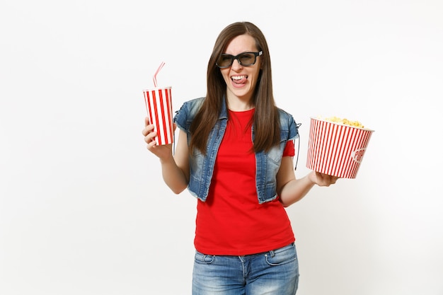 Portrait de jeune femme brune séduisante drôle dans des lunettes 3d regardant un film, tenant un seau de pop-corn et une tasse en plastique de soda ou de cola isolé sur fond blanc. Émotions dans le concept de cinéma.