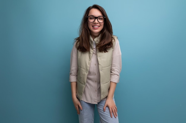 Portrait d'une jeune femme brune soignée corrigeant sa vue à l'aide de lunettes sur un studio