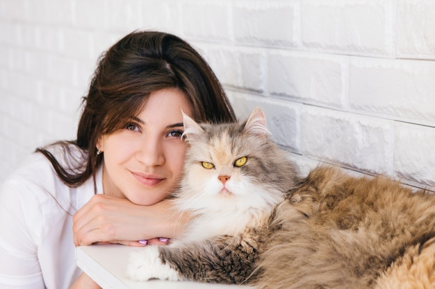 Portrait de jeune femme brune avec son chat pelucheux. Charmants animaux de compagnie et amour des gens pour eux