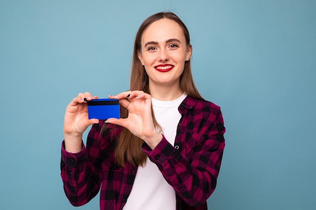 Portrait d'une jeune femme avec une carte bancaire sur fond bleu