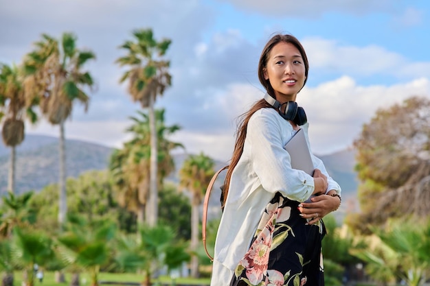 Portrait de jeune femme avec un casque à dos et un ordinateur portable dans ses mains copie espace