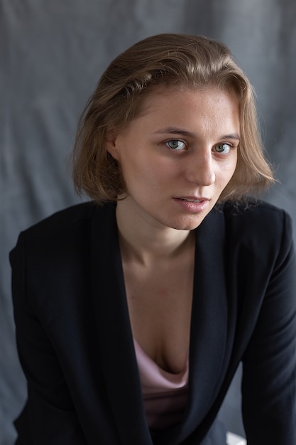 Portrait de jeune femme caucasienne aux cheveux courts posant en veste de costume noir