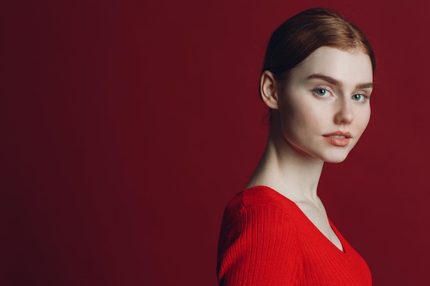 Portrait de jeune femme caucasienne aux cheveux roux gingembre sur fond rouge