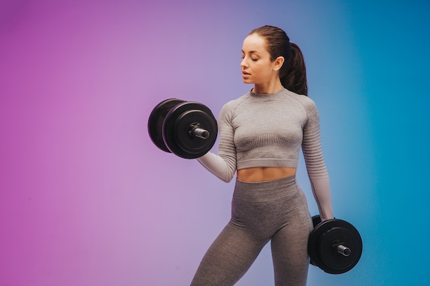 Portrait de jeune femme caucasienne fit et sportive sur fond dégradé