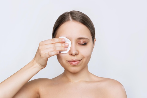 Portrait d'une jeune femme caucasienne nettoyant son visage avec un coton démaquillant les yeux