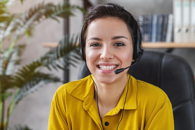 Portrait d'une jeune femme caucasienne souriante avec casque et microphone à l'intérieur