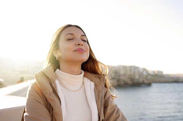 Portrait de jeune femme charmante respirant l'air frais se relaxant les yeux fermés sur la plage