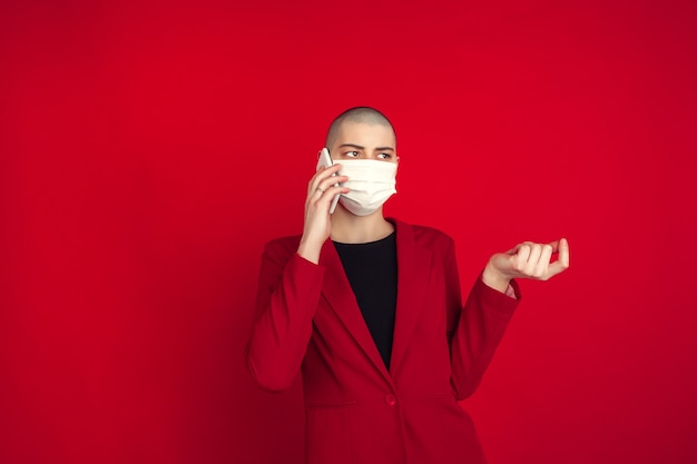 Portrait de jeune femme chauve caucasienne sur mur rouge