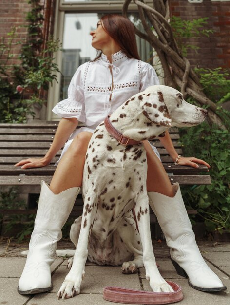 Photo portrait d'une jeune femme avec un chien assis sur un banc dans la rue