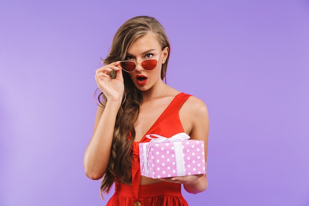 Portrait d'une jeune femme choquée en robe rouge posant