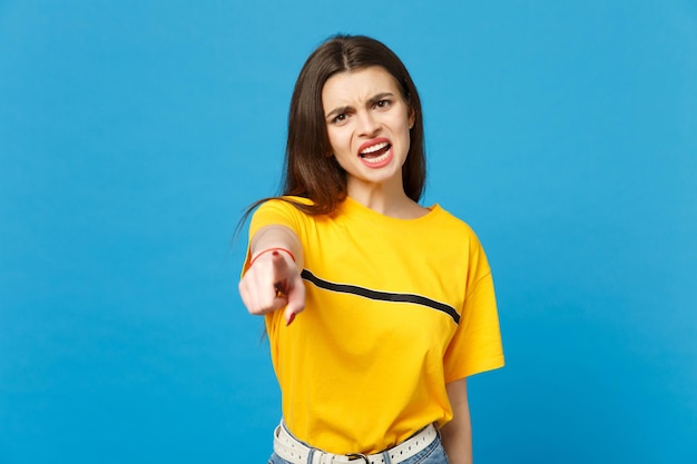 Portrait d'une jeune femme en colère irritée dans des vêtements décontractés vifs jurant, pointant l'index sur l'appareil photo isolé sur fond bleu vif en studio. Concept de style de vie des gens. Maquette de l'espace de copie.