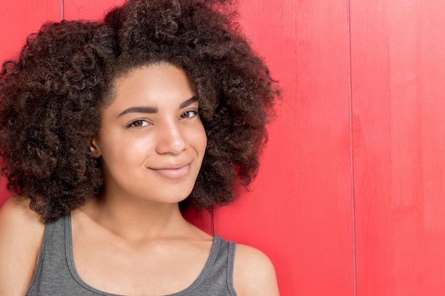 Portrait d'une jeune femme confiante posant sur un fond rouge