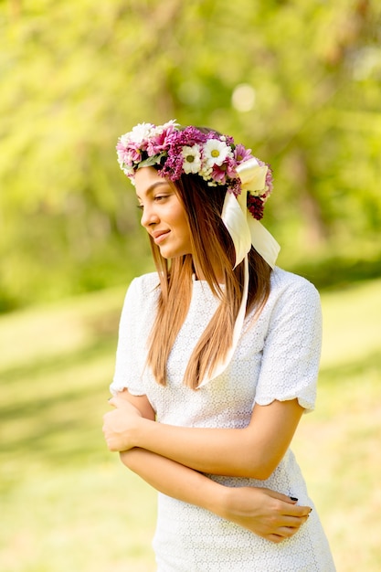 Portrait de jeune femme avec une couronne de fleurs fraîches sur la tête dans le parc