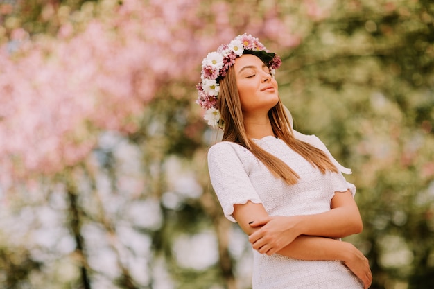 Portrait de jeune femme avec une couronne de fleurs fraîches sur la tête dans le parc