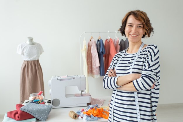 Portrait d'une jeune femme couturière coupeuse debout sur le mur de son bureau