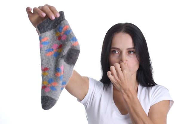 Portrait de jeune femme couvrant le nez et tenant la chaussette à la main. Odeur de chaussettes homme pour concept femme