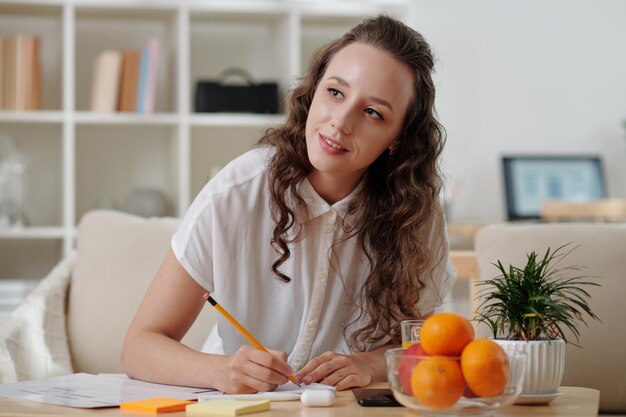 Portrait d'une jeune femme créative souriante travaillant sur la conception d'interfaces et dessinant des croquis