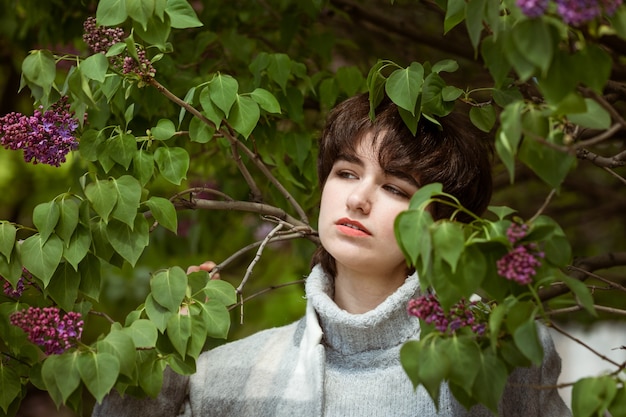 Portrait d'une jeune femme dans un buisson de lilas sur une journée de printemps ensoleillée