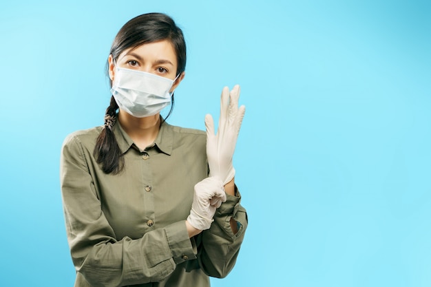 Photo portrait d'une jeune femme dans un masque médical mettant des gants de protection