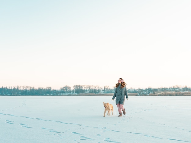 Portrait Jeune femme dans le parc d'hiver marchant avec son chien golden retriever. Amitié, animal de compagnie et humain.