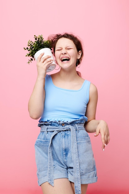 Portrait d'une jeune femme dans un t-shirt bleu et un short un arrière-plan isolé pot de fleurs inchangé