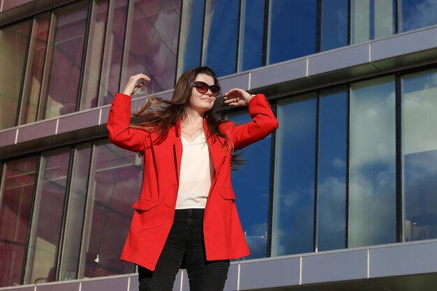 Portrait d'une jeune femme dans une veste rouge sur le fond des bâtiments en verre