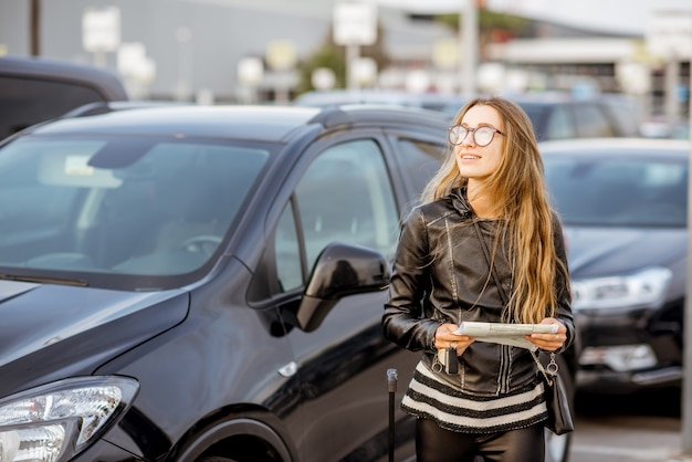 Portrait d'une jeune femme debout avec contrat de location à l'extérieur sur le parking près de l'aéroport