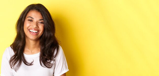 Photo portrait d'une jeune femme debout contre un mur jaune