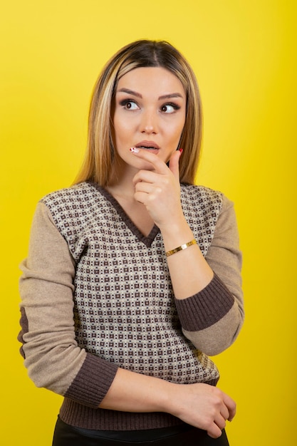 Portrait de jeune femme debout et regardant sur jaune.