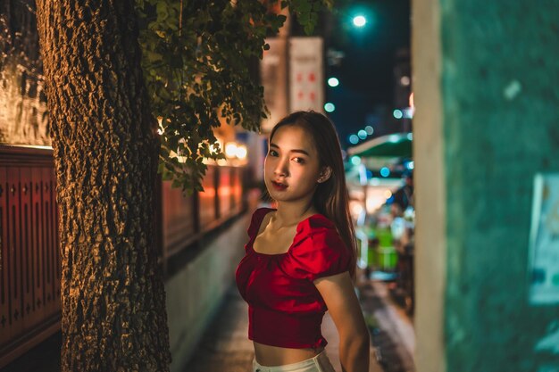 Portrait d'une jeune femme debout sur le trottoir de la ville la nuit.