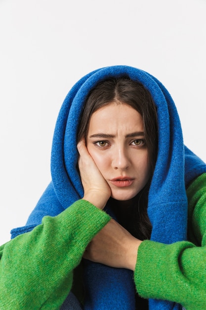 Portrait d'une jeune femme décontractée portant un pull onsized assis sur blanc