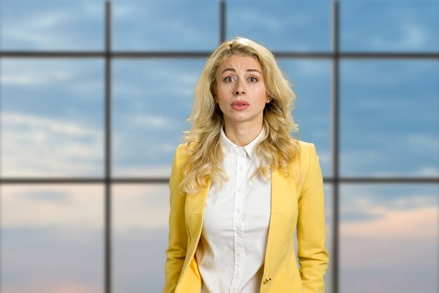 Portrait de jeune femme déçue. Belle blonde bouleversée à la confusion sur la fenêtre du bureau de ciel bleu. Expressions faciales humaines.