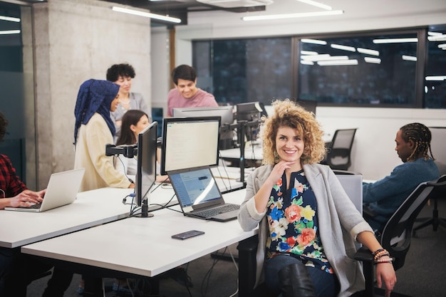 portrait d'une jeune femme développeur de logiciels au bureau de démarrage occupé avec son équipe commerciale multiethnique en arrière-plan